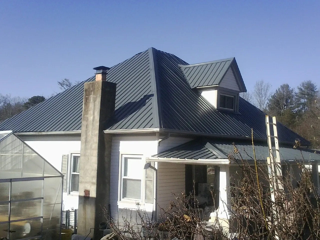 Dark blue standing seam metal roof on a white farmhouse with dormer — Slate & Tile Roof Repair by Roofing Brothers in Sheffield