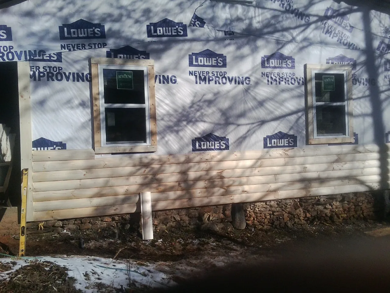 House wrap and new log siding going up on an exterior wall in Sheffield